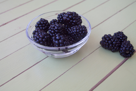 blackberries on transparent bowl on a green wooden table seen close upの写真素材