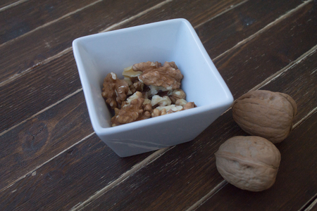 walnuts in a white bowl on a wooden table seen closelyの写真素材