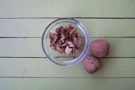 walnuts in a transparent bowl on a green wooden table seen from aboveの写真素材