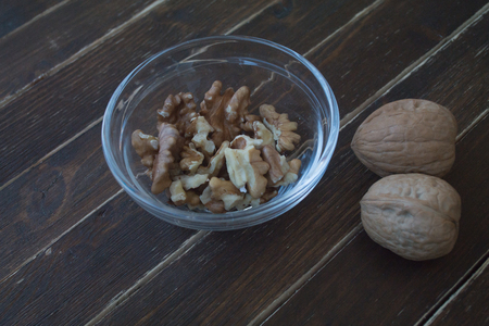 walnuts in a transparent bowl on a wooden table seen close upの写真素材