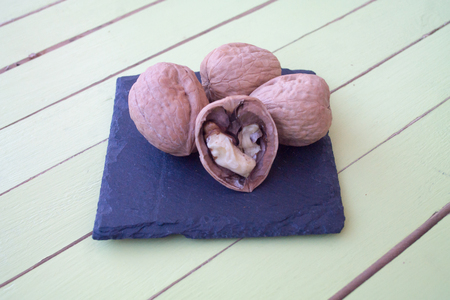 walnuts on a slate plate on a green wooden table seen close upの写真素材