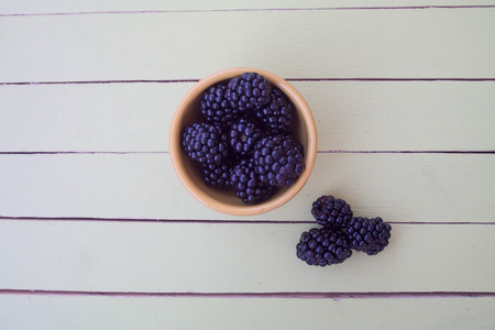 blackberries on yellow bowl on a green wooden table seen from aboveの写真素材