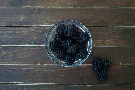 blackberries on transparent bowl on a wooden table seen from aboveの写真素材