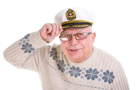 Closeup portrait of happy old senior man with a smile, white teeth and glasses in the boat captain cap touching visor, Isolated on white backgroundの写真素材