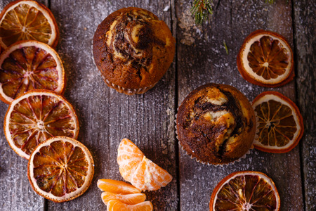 Xmas composition with holiday decoration - Homemade christmas cupcakes, sliced dried oranges on wooden background with spruce twigs and christmas toy. Christmas card. Space for textの写真素材