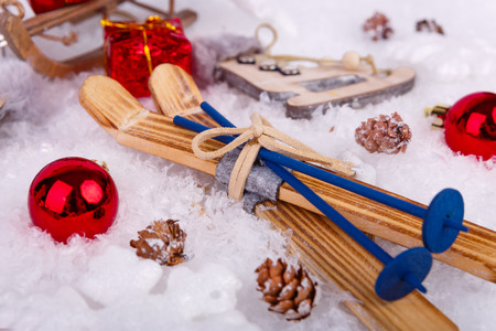 Xmas or new year composition with holiday decorations - little cristmas baubles, on snow with toy skates and skis, little gift box. Christmas cardの写真素材