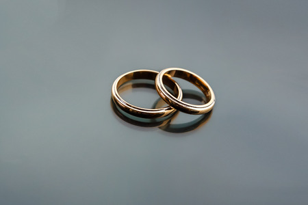 Celebratory accessories - two gold wedding rings for special day on glass grey backgroundの写真素材