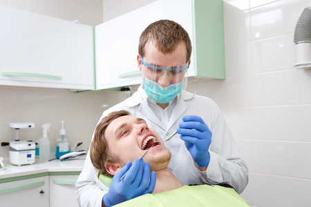 Young Man in dentost chair having teeth examined at dentists. Young Male dentistの写真素材