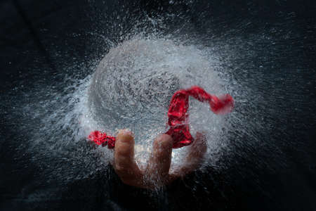 Balloon explosion filled with water held by a hand with black background