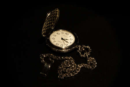 Vintage pocket watch on a black background. Black and white photo.