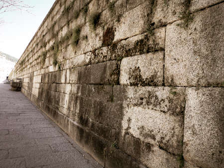 old stone wall in the city with moss and lichen on it