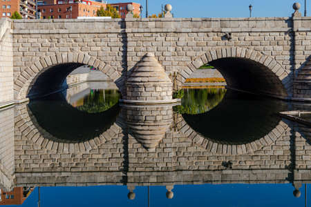 Segovia Bridge in Madrid reflected in the Manzanares River.  Urban landscape.  Stone bridge