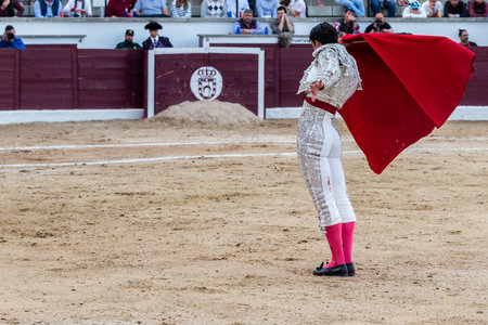 Madrid, Spain- April 30, 2022: Bullfight in San Martin de Valdeiglesias. Bullfighter with a crutch. Fighting bull. Bullfighter giving a muleta pass to the bull in a bullring.のeditorial素材