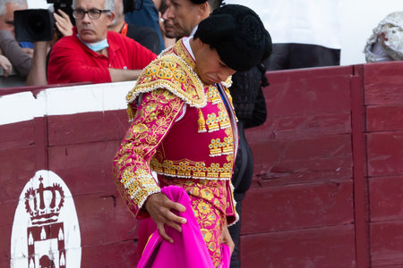 Madrid, Spain- April 30, 2022: Bullfight in San Martin de Valdeiglesias. Bullfighter with cape. Fighting bull. Bullfighter giving a capote pass to the bull in a bullring.のeditorial素材
