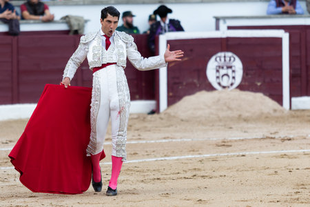 Madrid, Spain- April 30, 2022: Bullfight in San Martin de Valdeiglesias. Bullfighter with a crutch. Fighting bull. Bullfighter giving a muleta pass to the bull in a bullring.のeditorial素材