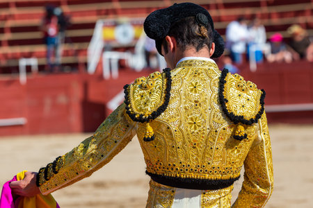 Madrid, Spain- April 30, 2022: Bullfight in San Martin de Valdeiglesias. Bullfighter with cape. Fighting bull. Bullfighter giving a capote pass to the bull in a bullring.のeditorial素材