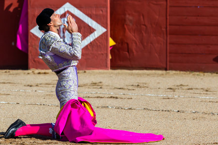 Madrid, Spain- April 30, 2022: Bullfight in San Martin de Valdeiglesias. Bullfighter with cape. Fighting bull. Bullfighter giving a capote pass to the bull in a bullring.のeditorial素材