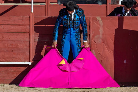 Madrid, Spain- April 30, 2022: Bullfight in San Martin de Valdeiglesias. Bullfighter with cape. Fighting bull. Bullfighter giving a capote pass to the bull in a bullring.のeditorial素材