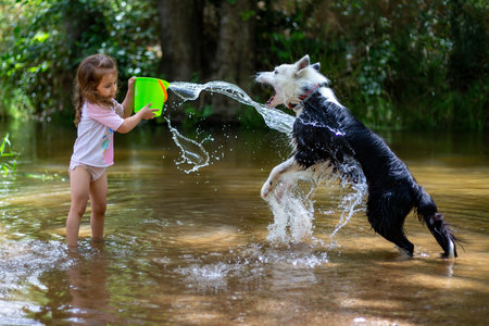 Little girl playing with some plastic buckets in the river. Girl with swimsuit and t-shirt. Children's photo in summer.の写真素材