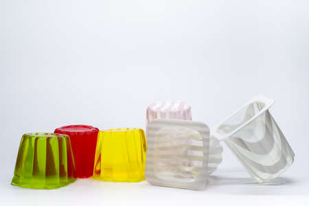 Color jellies and plastic cups on white background. Sugar-free desserts. Food and vitamins. Colored sweets.の写真素材
