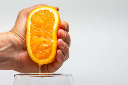 Macro photo of an orange squeezed with a hand. Orangejuice. Side photo. Citrus fruit juice. Natural juices.の写真素材