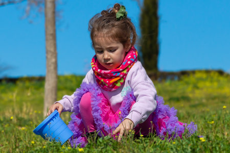 Blonde little girl in sweatshirt and scarf. 3 year old blonde girl. Children in the park. Funny photos.の写真素材