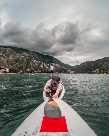 Amazing point of view with happy tourists on SUP stand up paddle board  with view to Natural and Culturo-Historical Region of Kotor in Kotor bay (Boka Kotorska), Montenegro, Europeの写真素材