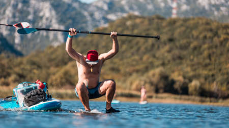 Young athletic man jumps from SUP stand up paddle board in the river on a hot summer dayの写真素材