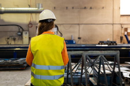 Rear view of an industrial woman engineer with smartphone in a factory, workingの写真素材