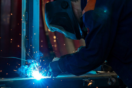 welder and welding sparks, construction and metal work industrial concept, metal welding with sparks