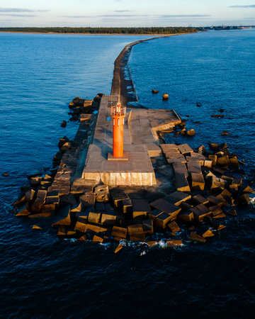 An orange lighthouse at the end of the Mangalsala or Eastern pier in Riga, Latvia where the river Daugava flows into the Baltic Sea.の写真素材