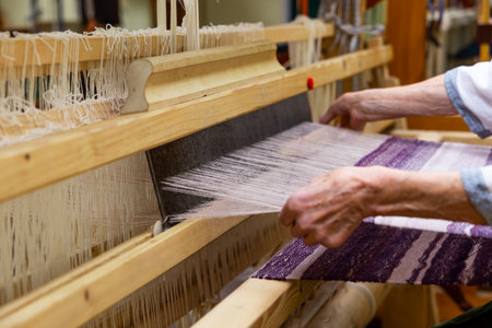 Woman is warping a wooden handloom. Hands holding a heddle hook and threading the table loom. Weaving toolsの写真素材