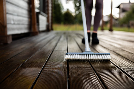 Woman washes a wooden terrace before painting it in her modern private houseの写真素材