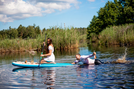 Beautiful woman and man have fun on sup, Inflatable stand up paddle boardの写真素材
