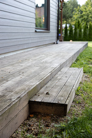Old weathered wooden deck and new facade of a modern houseの写真素材
