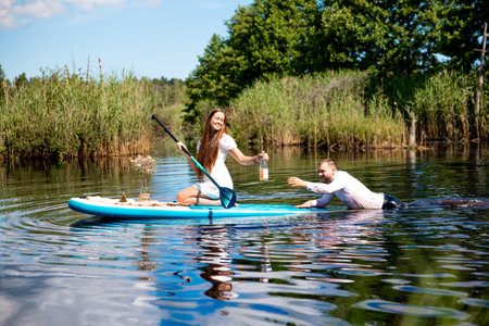 Beautiful woman and man have fun on sup, Inflatable stand up paddle boardの写真素材