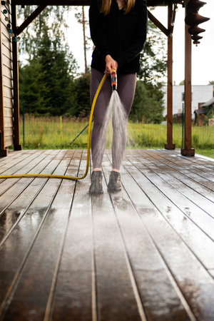 Woman washes a wooden terrace before painting it in her modern private houseの写真素材