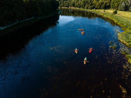 Tranquil kayaking scene on a wide river, surrounded by lush forest and clear skiesの写真素材