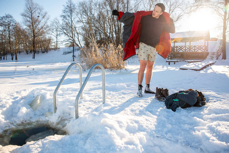 Man drying off  after cold winter swimming in the golden sunlight of a snowy landscapeの写真素材