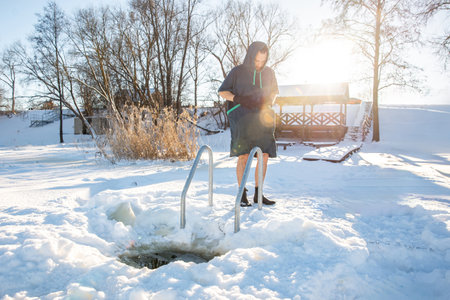 Man standing by a winter swimming hole, ready to embrace the cold in a snowy landscapeの写真素材