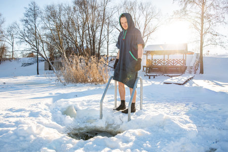 Man standing by a winter swimming hole, ready to embrace the cold in a snowy landscapeの写真素材