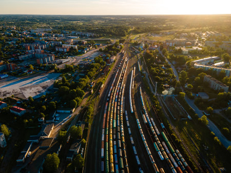 Aerial View of Bustling Train Yard Adjacent to a Picturesque Urban Landscape at Sunsetの写真素材