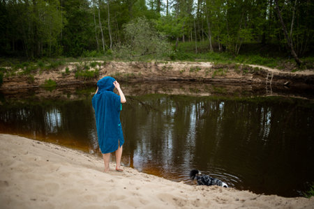 Woman in Blue Poncho poses by Riverside with Her Dogの写真素材