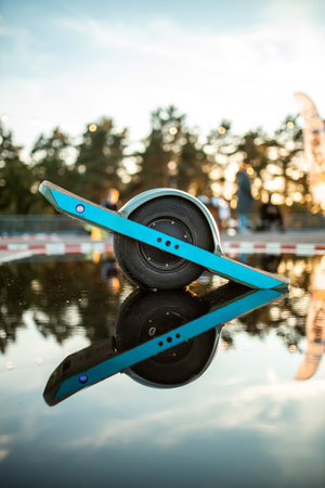 innovative one wheel electric skateboard reflects on water, showcasing alternative urban transportの写真素材