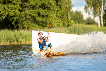 Young man wakeboarding on a lake, making raley, frontroll and jumping the kickers and sliders. Wakeboard.の写真素材