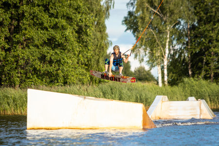 Young man wakeboarding on a lake, making raley, frontroll and jumping the kickers and sliders. Wakeboard.の写真素材