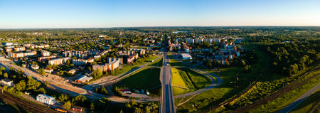 Panoramic Aerial View of Cityscape with Roads and Greenery Under Golden Sunlightの写真素材