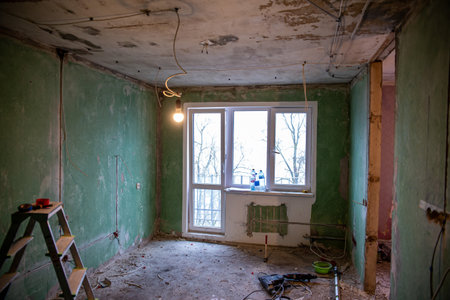 Abandoned building interior in disrepair with debris, exposed pipes, and missing doors awaiting renovationの写真素材