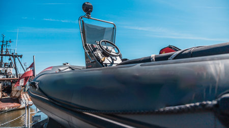 close-up view of a military inflatable boat on the dock with ship cranes in the background under clear blue skiesの写真素材