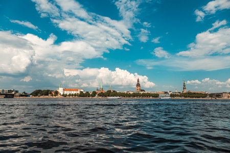 Two military speed boats patrolling the river with a historic city skyline and fluffy white clouds in the backgroundの写真素材